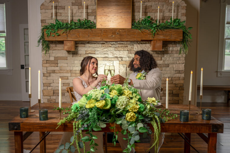 Bride and groom sitting at a sweetheart table in front of the fireplace at 1860 Schulhaus Venue in New Melle, MO