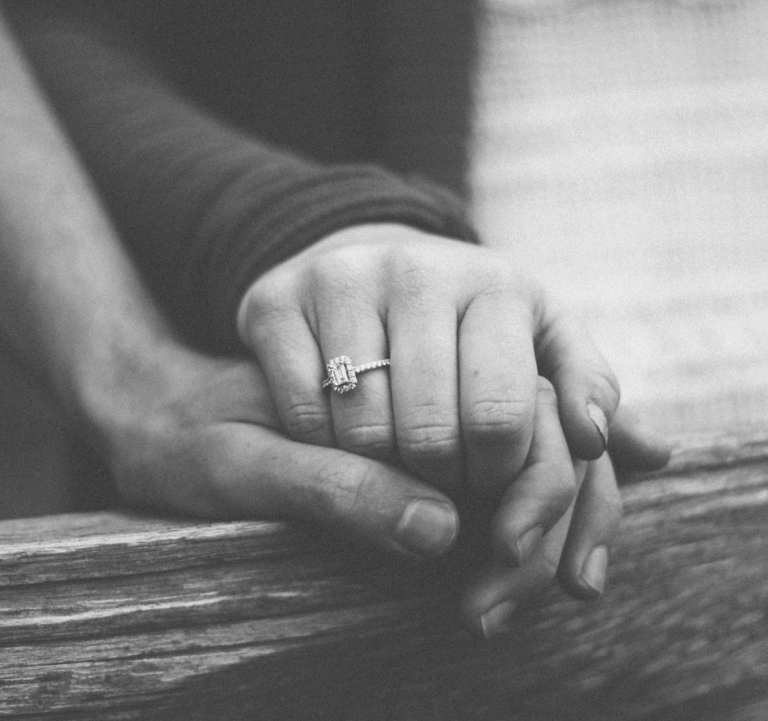 Couple holding hands with woman's engagement ring showing