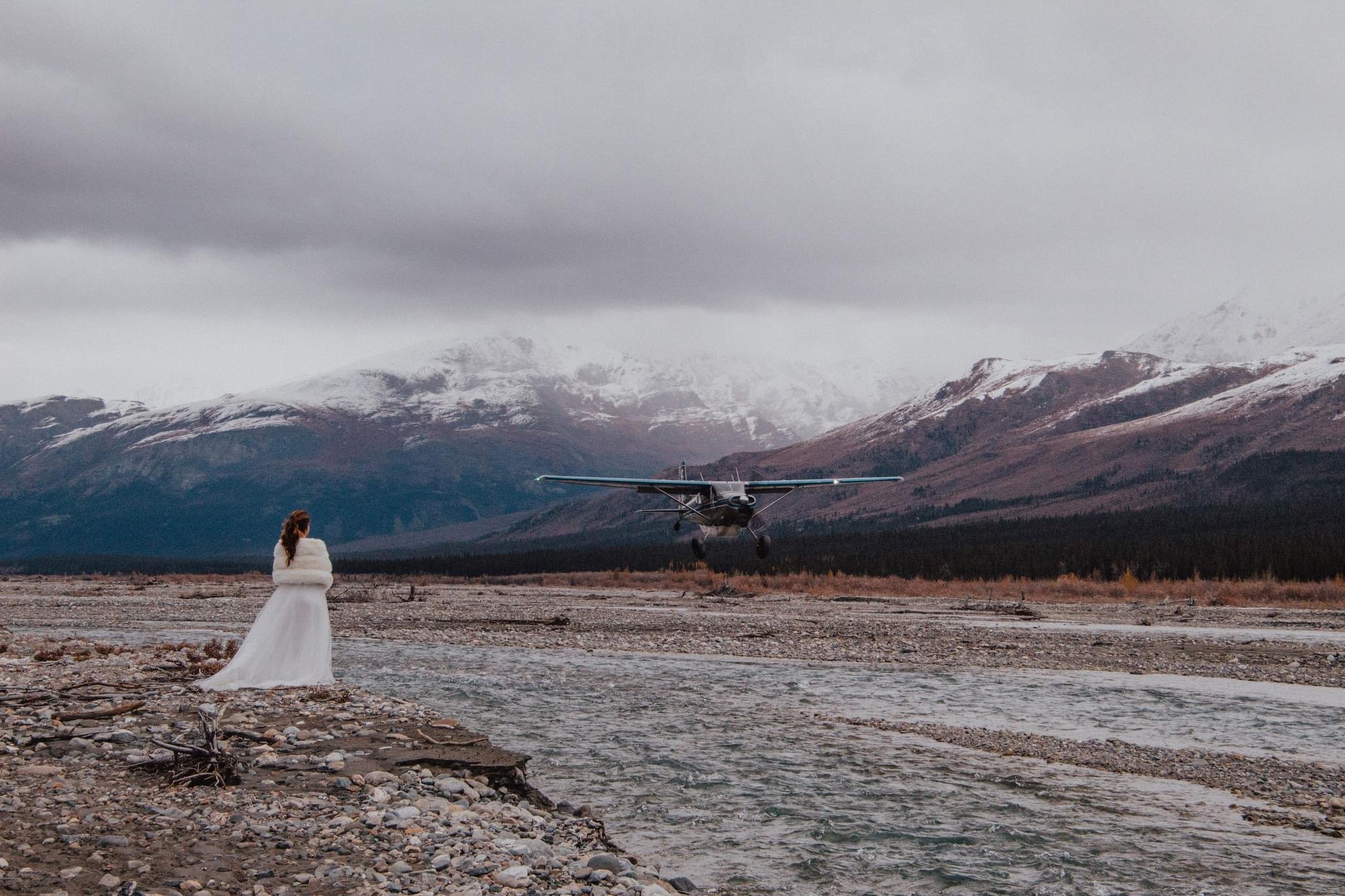 Bride staring away from camera towards a plane in front of a mountain range