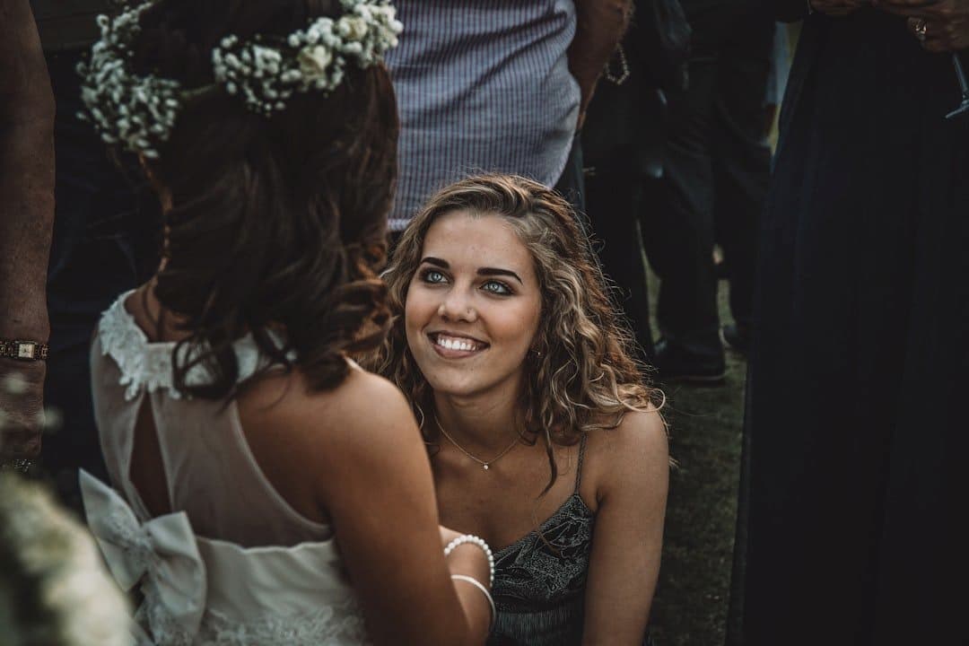 woman kneeling down and smiling up at young girl who appears to be a flower girl